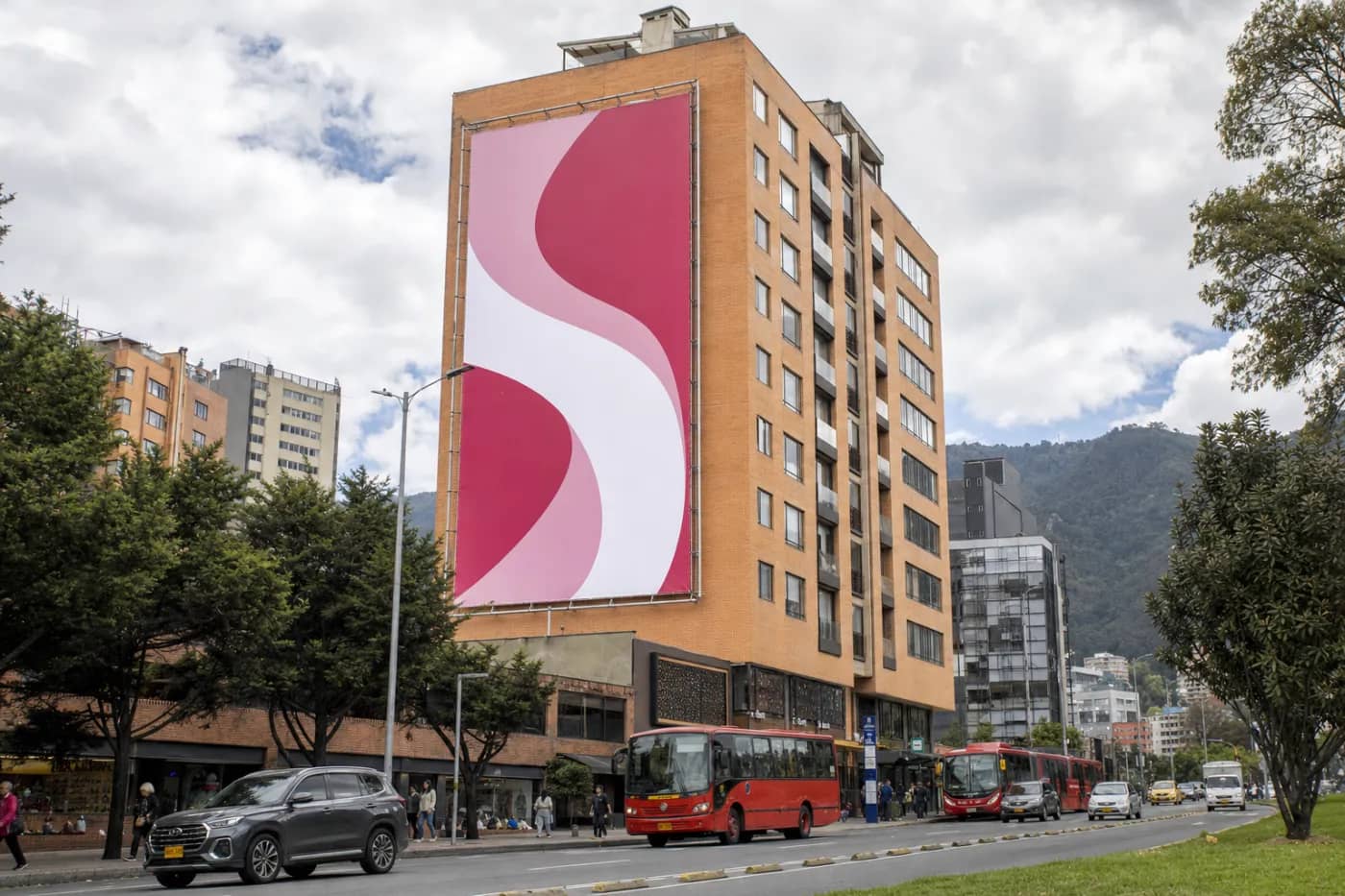 Bastidor publicitario de gran formato instalado en la culata de un edificio frente a una avenida de Bogotá, con el marco metálico visible
