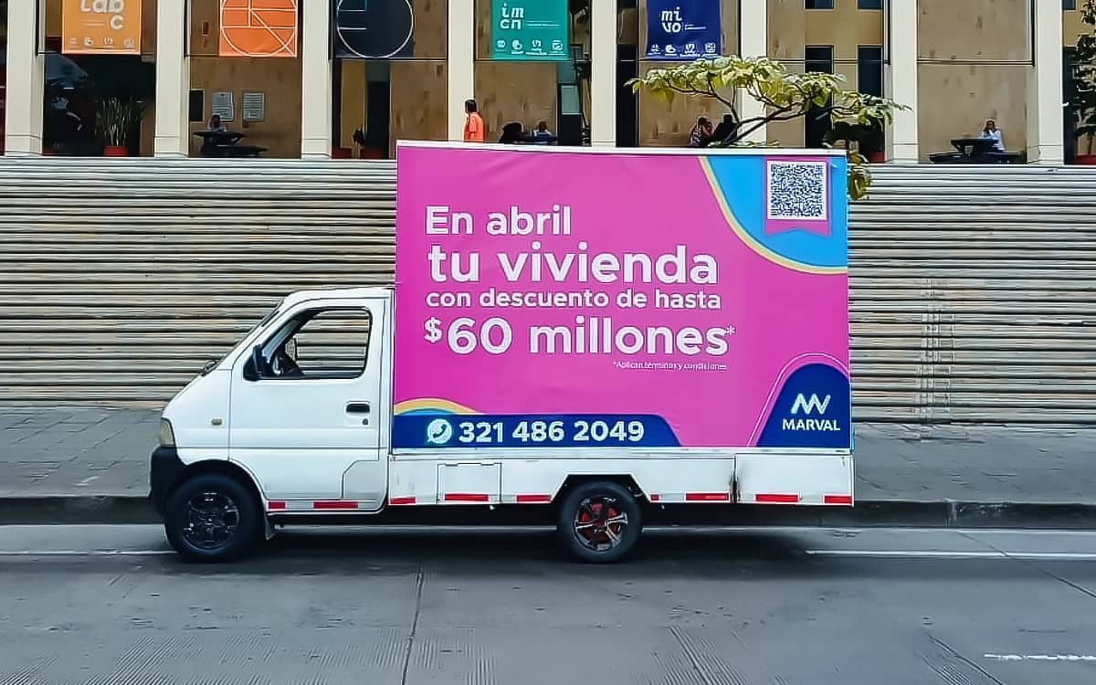 Carro valla de Bagu Medios en recorrido por Bogotá; el carro pantalla LED usa el mismo tipo de vehículo con pantalla digital en lugar de lona impresa