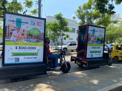 Dos moto vallas de Bagu Medios con remolque y valla impresa por ambas caras en recorrido por una calle de la ciudad