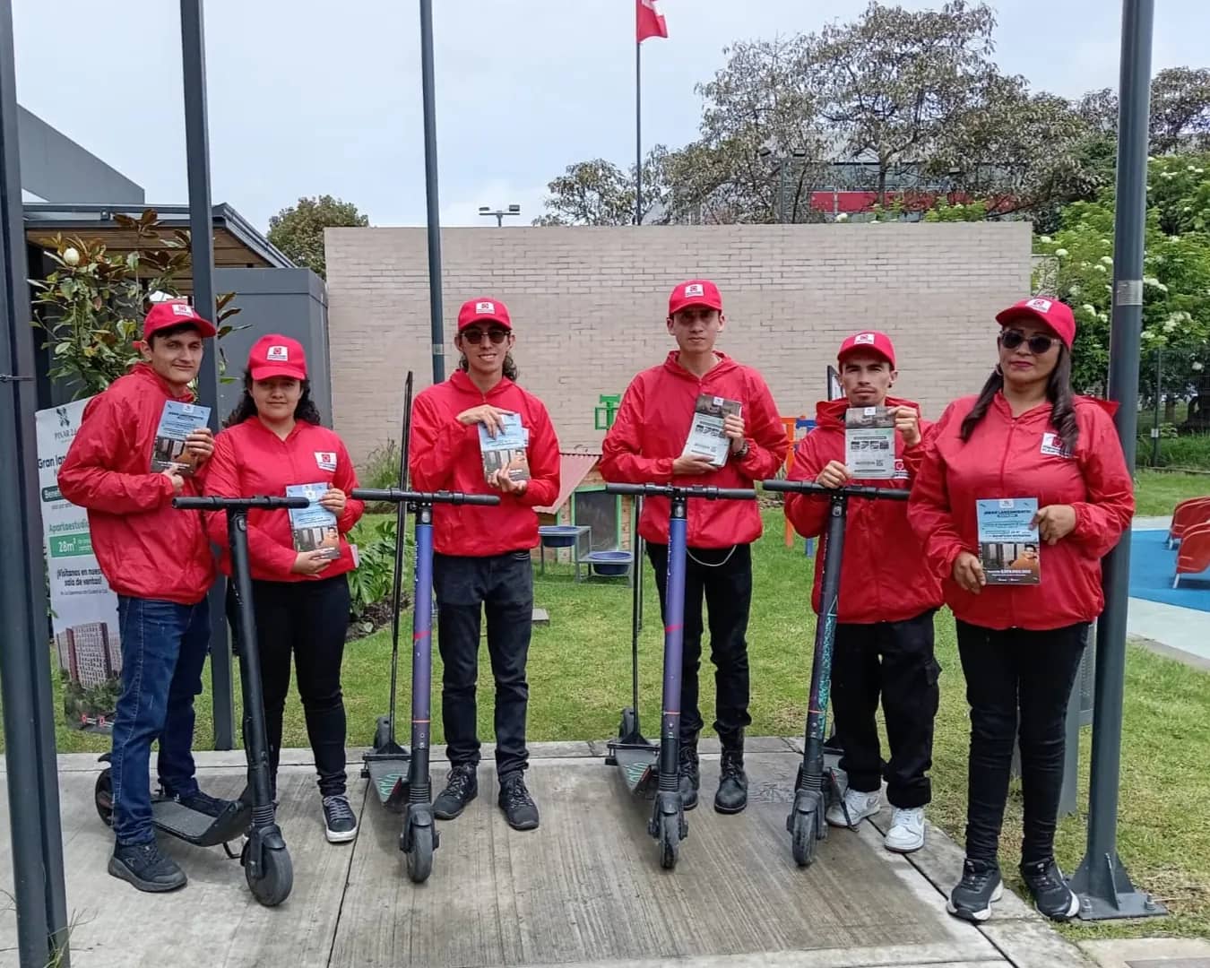 Equipo de seis promotores de Bagu Medios con scooter valla y material impreso para entregar